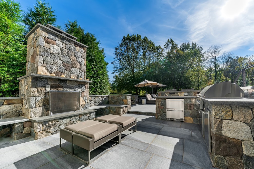 This is an example of a classic back patio in New York with an outdoor kitchen, concrete paving and no cover.
