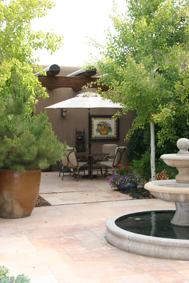 Пример оригинального дизайна: двор в стиле фьюжн с фонтаном и покрытием из каменной брусчатки