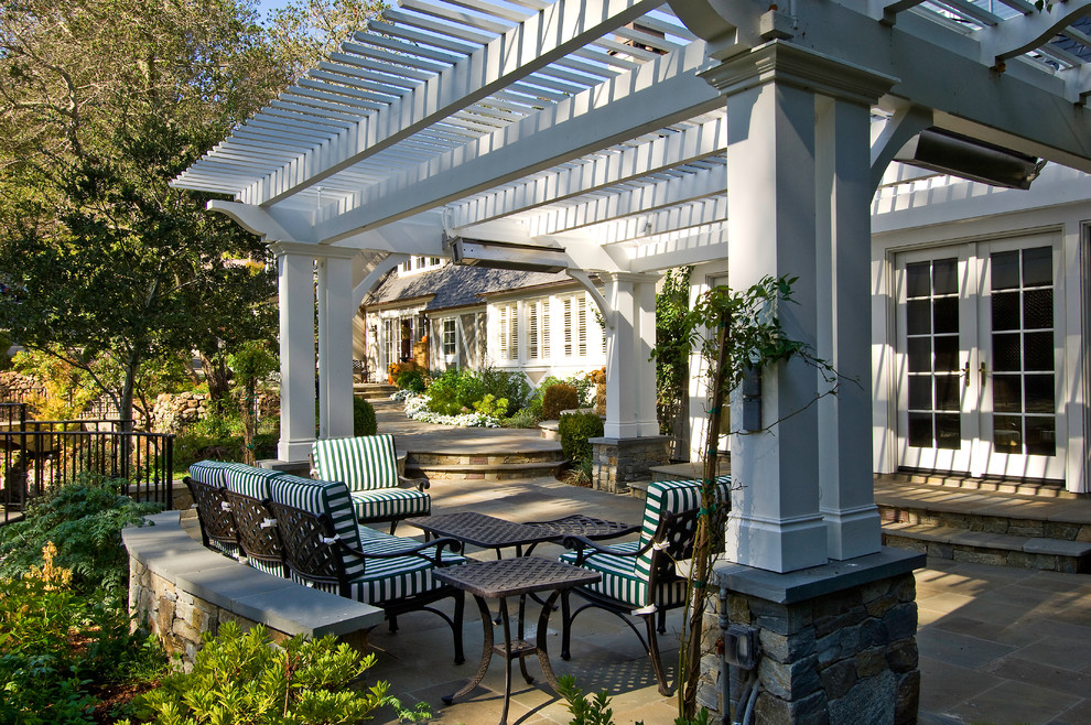 Imagen de patio clásico de tamaño medio en patio trasero con adoquines de hormigón y pérgola