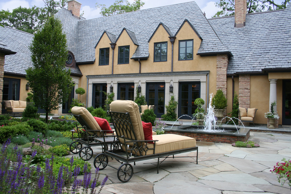 На фото: двор в классическом стиле с фонтаном и покрытием из каменной брусчатки без защиты от солнца