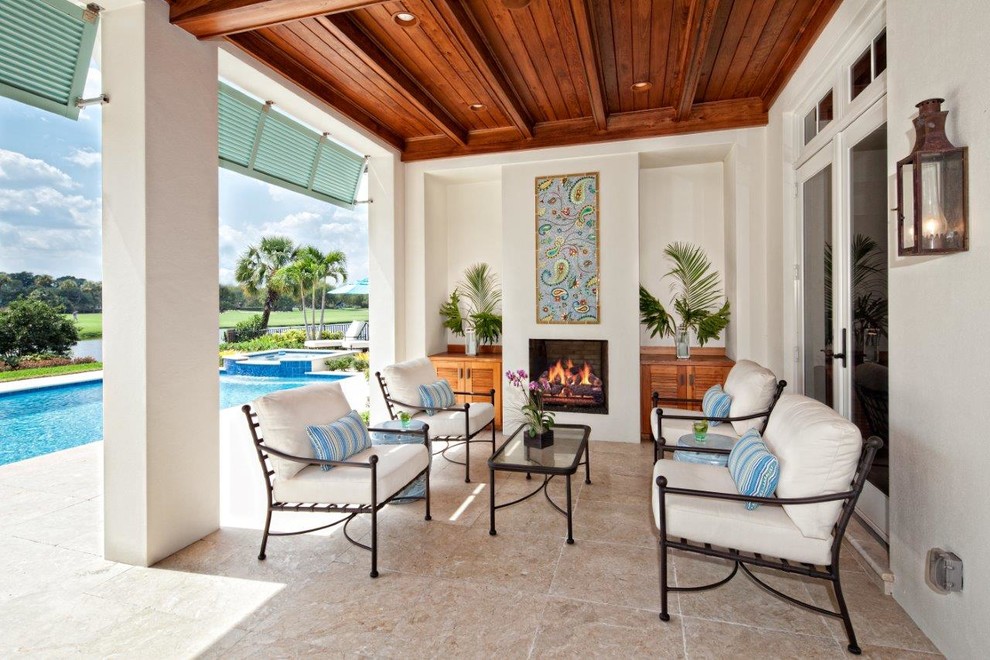 Design ideas for an expansive classic patio in Miami with a fire feature, natural stone paving and a roof extension.