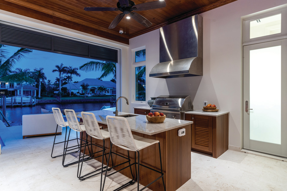 Photo of a classic back patio in Miami with an outdoor kitchen and a roof extension.