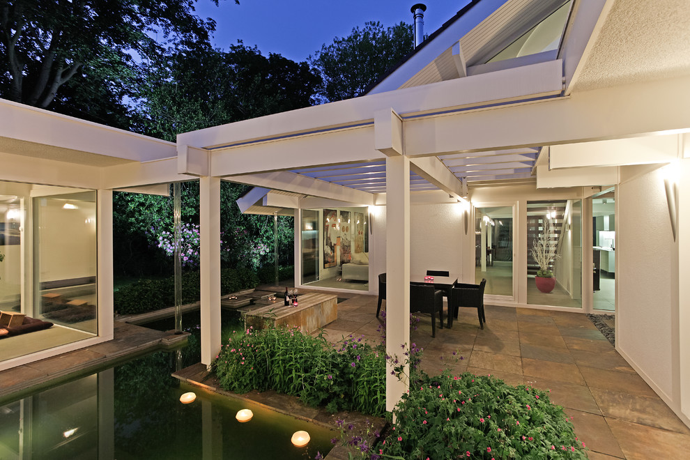 Cette image montre une grande terrasse latérale design avec une extension de toiture.