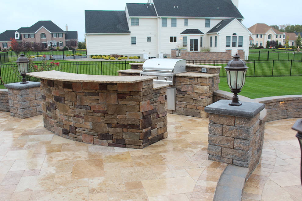 Aménagement d'une terrasse arrière classique de taille moyenne avec une cuisine d'été et des pavés en pierre naturelle.