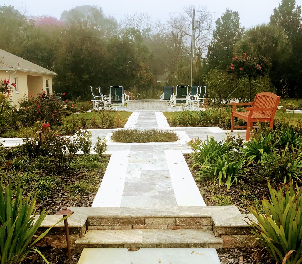 Immagine di un patio o portico minimal dietro casa con un focolare, pavimentazioni in pietra naturale e una pergola