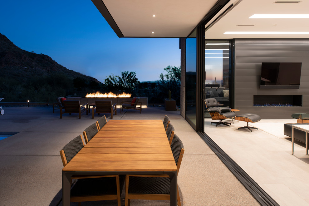 Cette photo montre une terrasse moderne de taille moyenne avec un foyer extérieur, une dalle de béton et une extension de toiture.