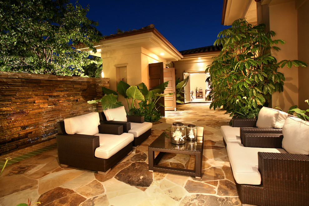 This is an example of a mediterranean back patio in Orange County with natural stone paving and no cover.