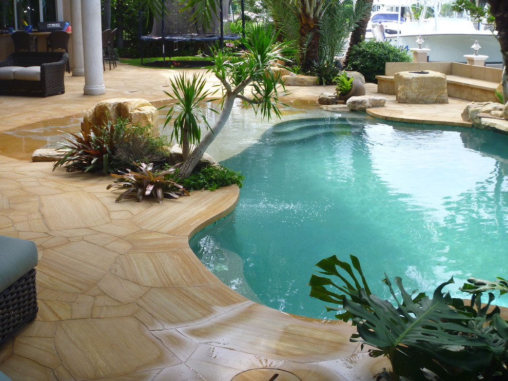 Idee per un patio o portico tropicale dietro casa con pavimentazioni in pietra naturale