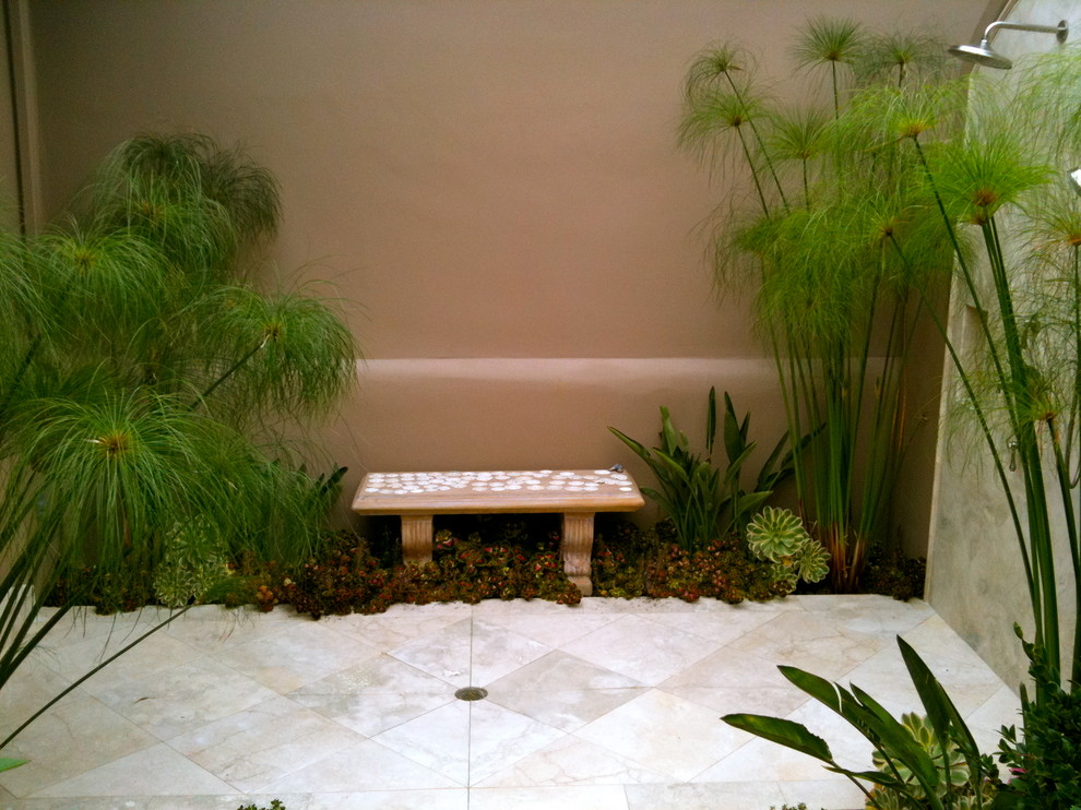 Imagen de patio mediterráneo con ducha exterior y suelo de baldosas
