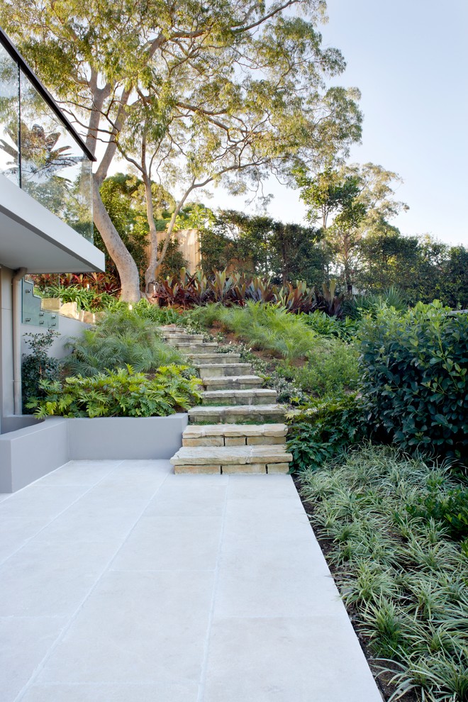 Idée de décoration pour une grande terrasse arrière design avec des pavés en pierre naturelle.