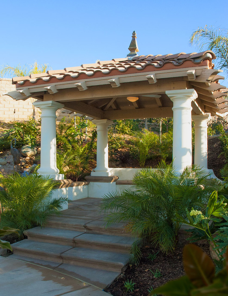 Idee per un patio o portico tropicale con un gazebo o capanno e scale