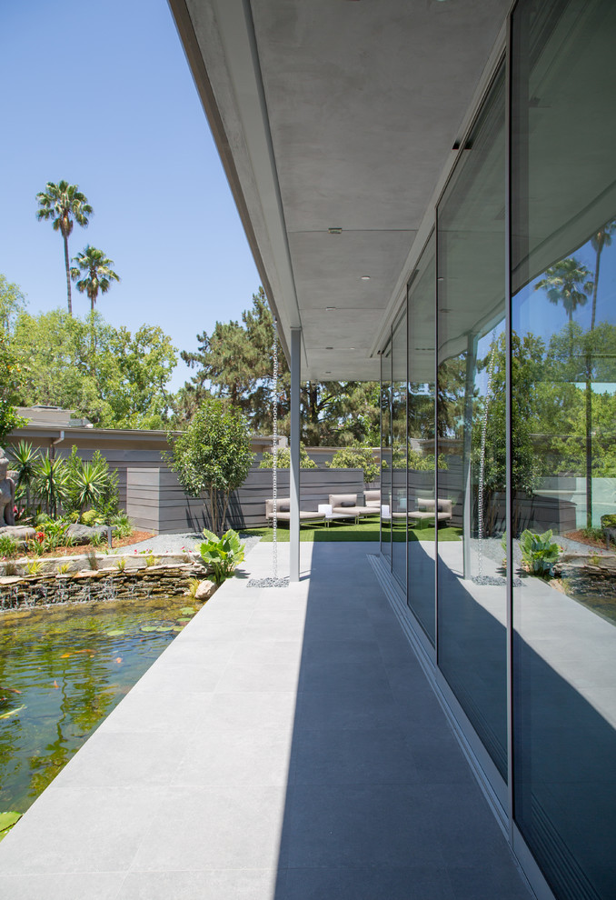 Design ideas for a contemporary back patio in Los Angeles with concrete slabs and a roof extension.