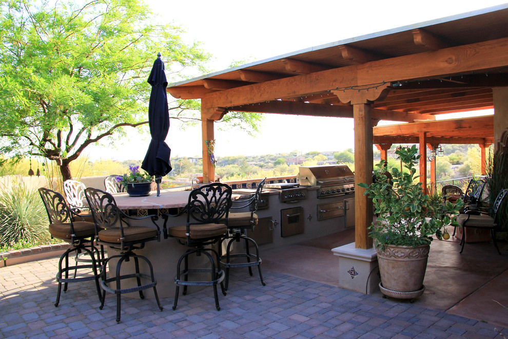 Mid-sized mediterranean backyard patio in Phoenix with an outdoor kitchen, brick pavers and a roof extension.