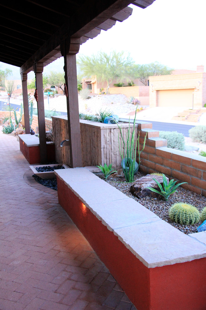 Ejemplo de patio de estilo americano de tamaño medio en patio trasero y anexo de casas con adoquines de ladrillo y fuente