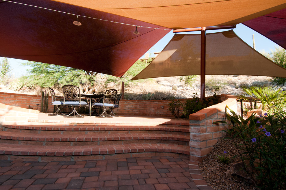 Modelo de patio de estilo americano de tamaño medio en patio trasero con adoquines de ladrillo y toldo