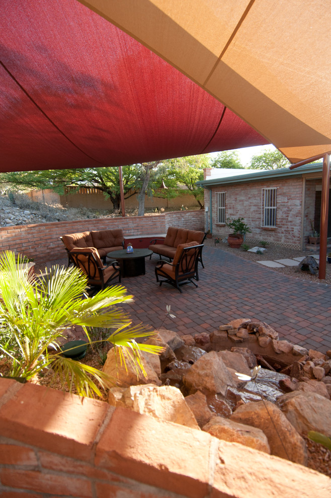 Idee per un patio o portico stile americano di medie dimensioni e dietro casa con pavimentazioni in mattoni e un parasole