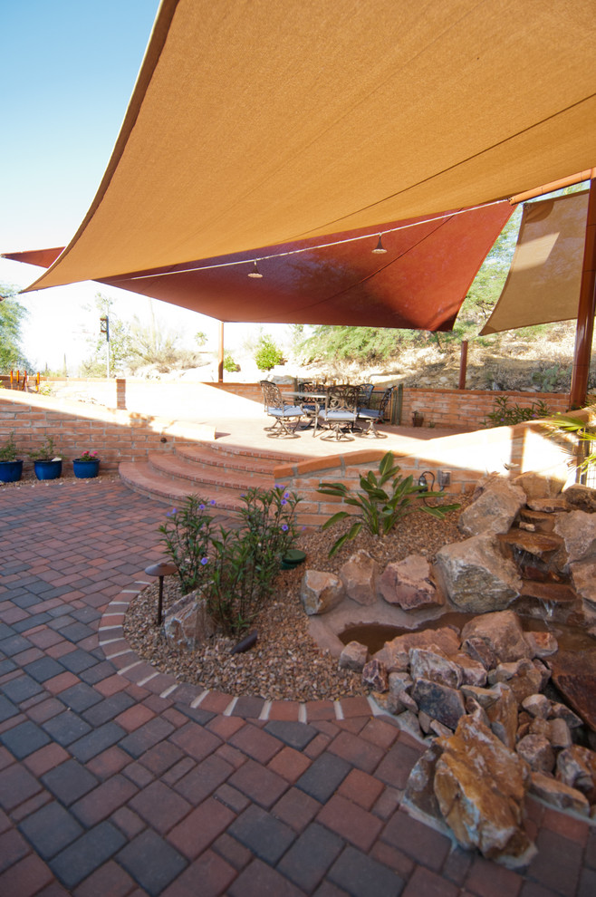 Foto di un patio o portico american style di medie dimensioni e dietro casa con pavimentazioni in mattoni e un parasole