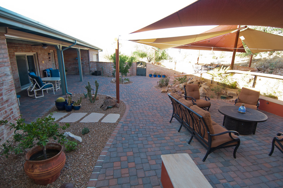 This is an example of a medium sized back patio in Phoenix with brick paving and an awning.