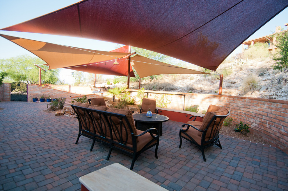 Immagine di un patio o portico stile americano di medie dimensioni e dietro casa con pavimentazioni in mattoni e un parasole