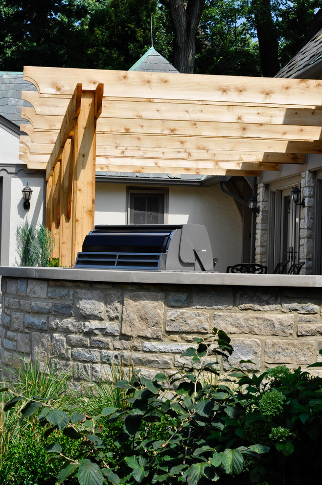 На фото: пергола во дворе частного дома на заднем дворе в классическом стиле с летней кухней и покрытием из каменной брусчатки