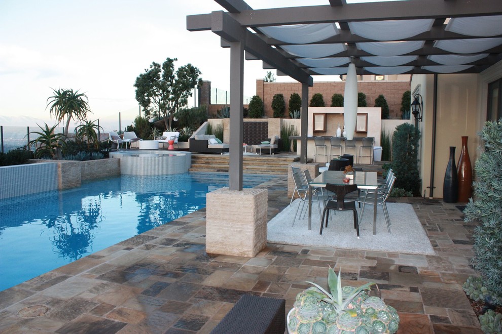 Inspiration for a large contemporary backyard stone patio kitchen remodel in Orange County with a pergola