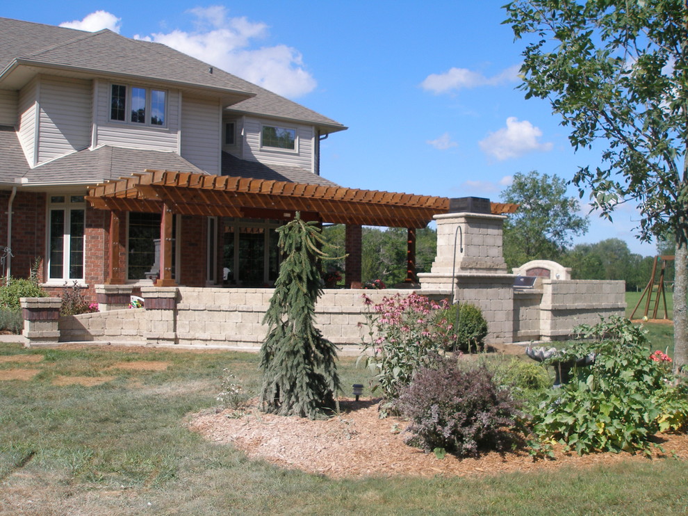 Exemple d'une grande terrasse arrière chic avec un foyer extérieur, des pavés en pierre naturelle et une pergola.