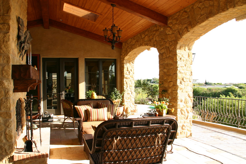 This is an example of a medium sized mediterranean back patio in Orange County with a fire feature and a roof extension.