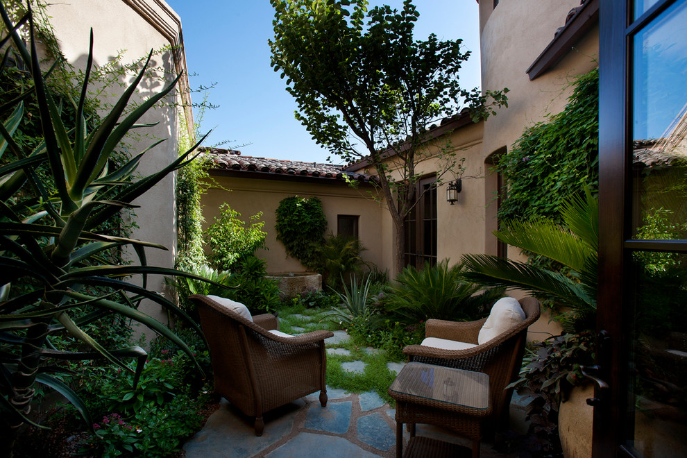 Inspiration for a small mediterranean backyard stone patio fountain remodel in Phoenix with a roof extension