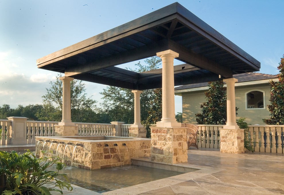 Diseño de patio mediterráneo de tamaño medio en patio trasero con fuente, adoquines de piedra natural y pérgola