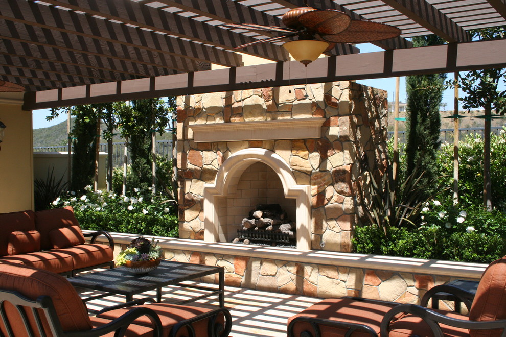 Ispirazione per un grande patio o portico mediterraneo dietro casa con pavimentazioni in pietra naturale e un caminetto