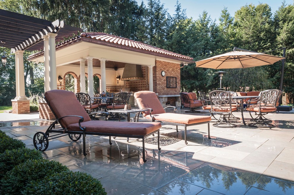 Foto di un grande patio o portico mediterraneo dietro casa con pavimentazioni in pietra naturale e una pergola