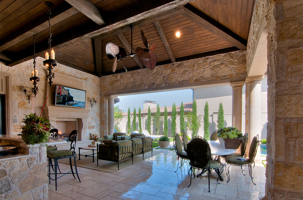 Immagine di un ampio patio o portico mediterraneo dietro casa con piastrelle e un tetto a sbalzo