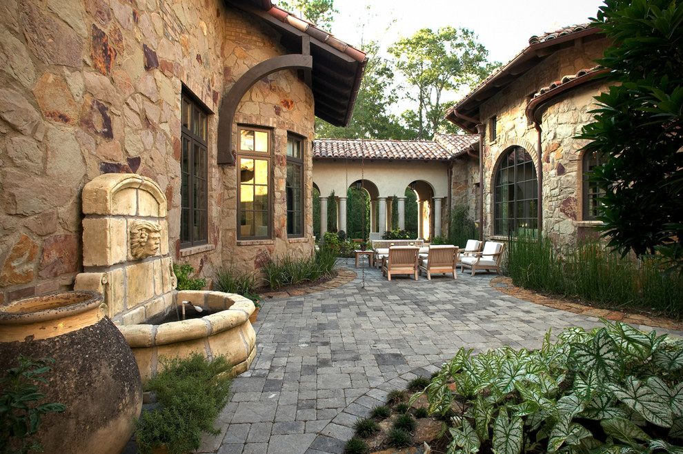 Imagen de patio rústico extra grande sin cubierta en patio con fuente y adoquines de piedra natural