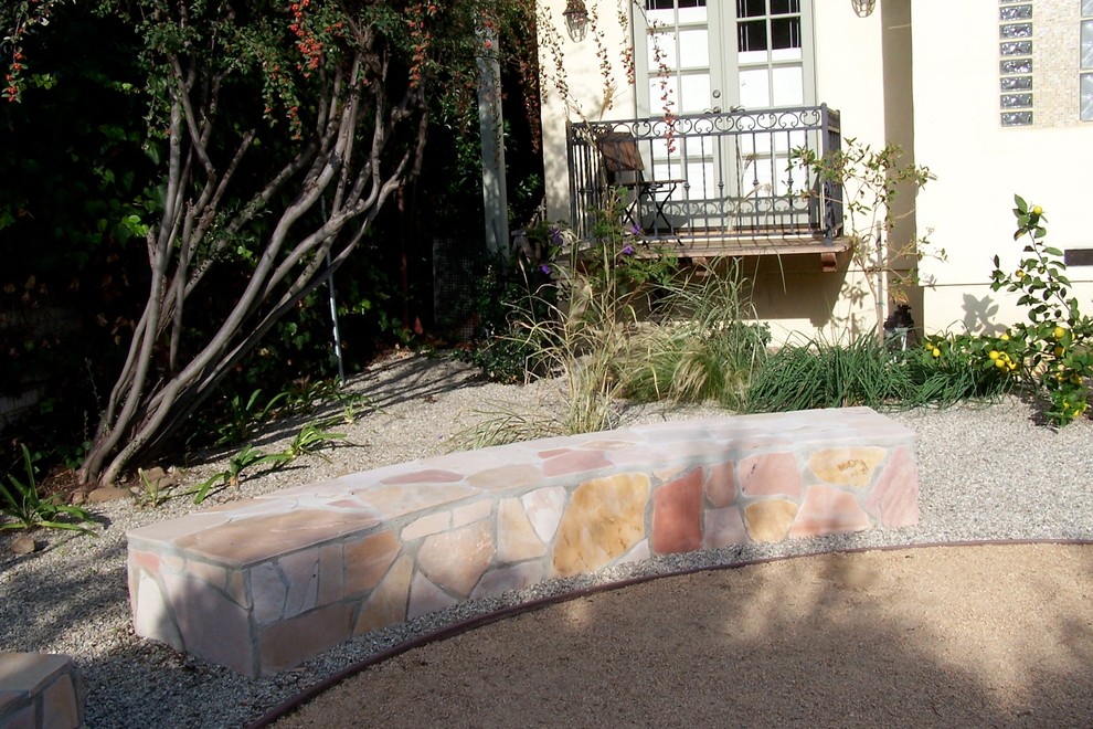 Diseño de patio mediterráneo de tamaño medio sin cubierta en patio trasero con brasero y gravilla