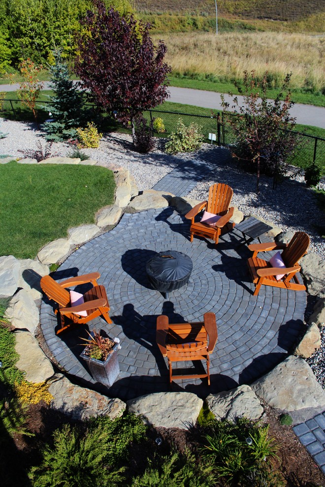 Elegant backyard concrete paver patio photo in Calgary with a fire pit and no cover