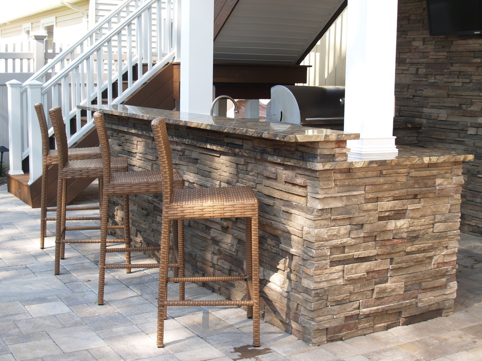 Exemple d'une terrasse arrière craftsman de taille moyenne avec une cuisine d'été, des pavés en pierre naturelle et une pergola.