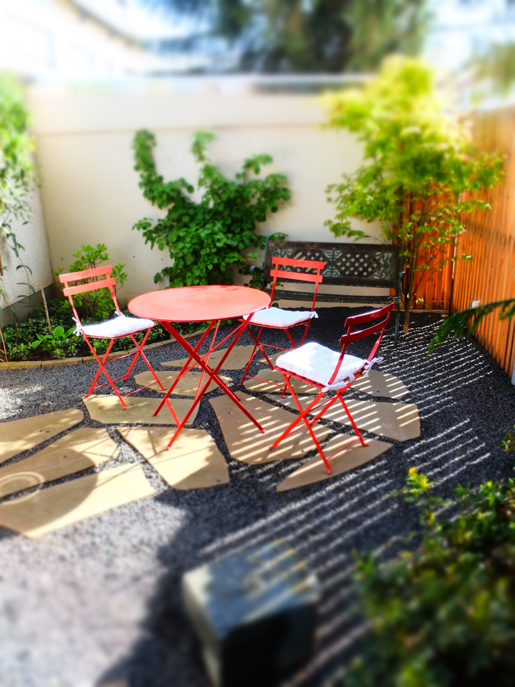 Small midcentury side patio in Cologne with gravel.