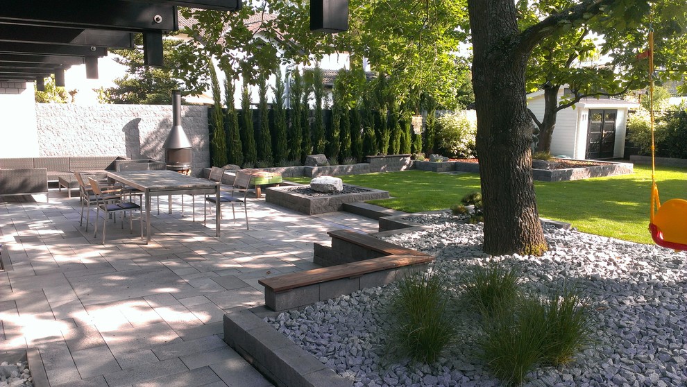 Design ideas for a large contemporary patio in Frankfurt with a roof extension and a fireplace.
