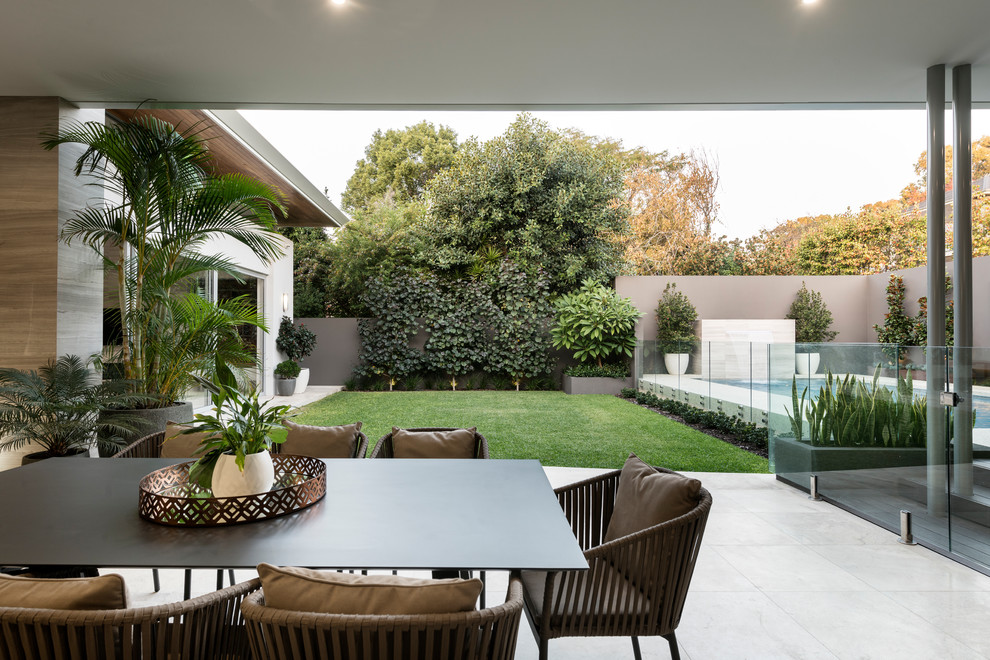 Idées déco pour une très grande terrasse arrière contemporaine avec une cuisine d'été, des pavés en pierre naturelle et une extension de toiture.