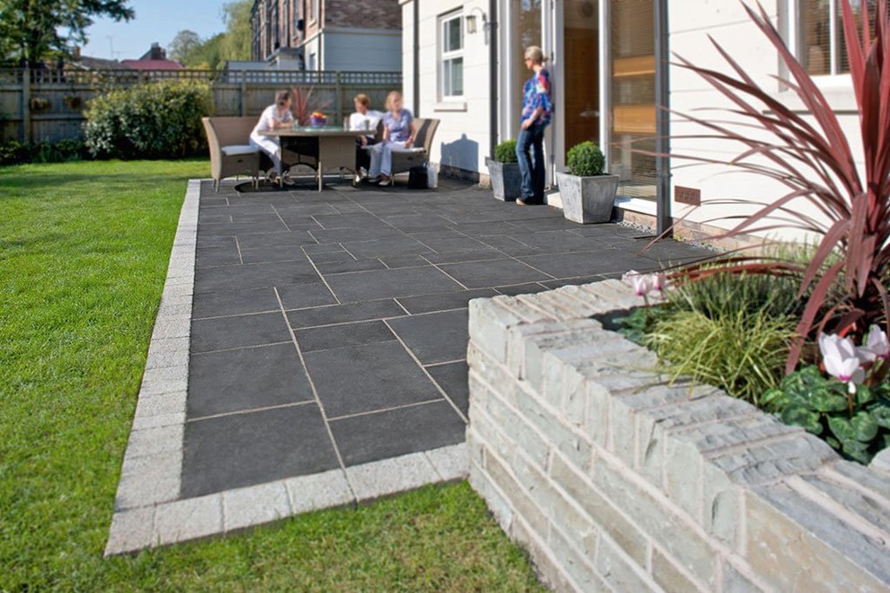 Contemporary back patio in Other with natural stone paving.