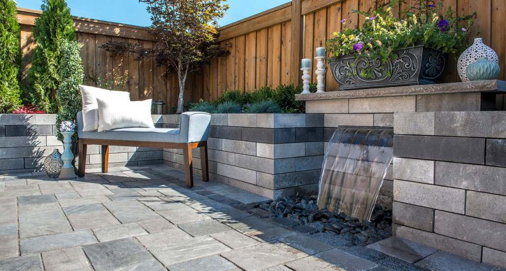 Diseño de patio moderno en patio trasero con fuente y adoquines de hormigón