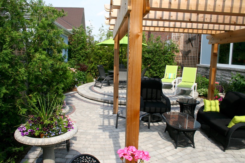 Aménagement d'une terrasse avec des plantes en pots arrière classique de taille moyenne avec des pavés en pierre naturelle et une pergola.