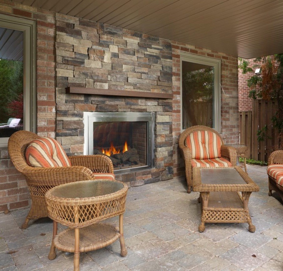 Design ideas for a medium sized classic back patio in Toronto with a fire feature, a roof extension and natural stone paving.