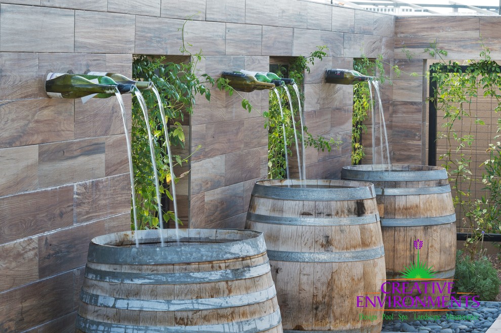 フェニックスにある高級な中くらいなサンタフェスタイルのおしゃれな裏庭のテラス (噴水、砂利舗装、日よけなし) の写真