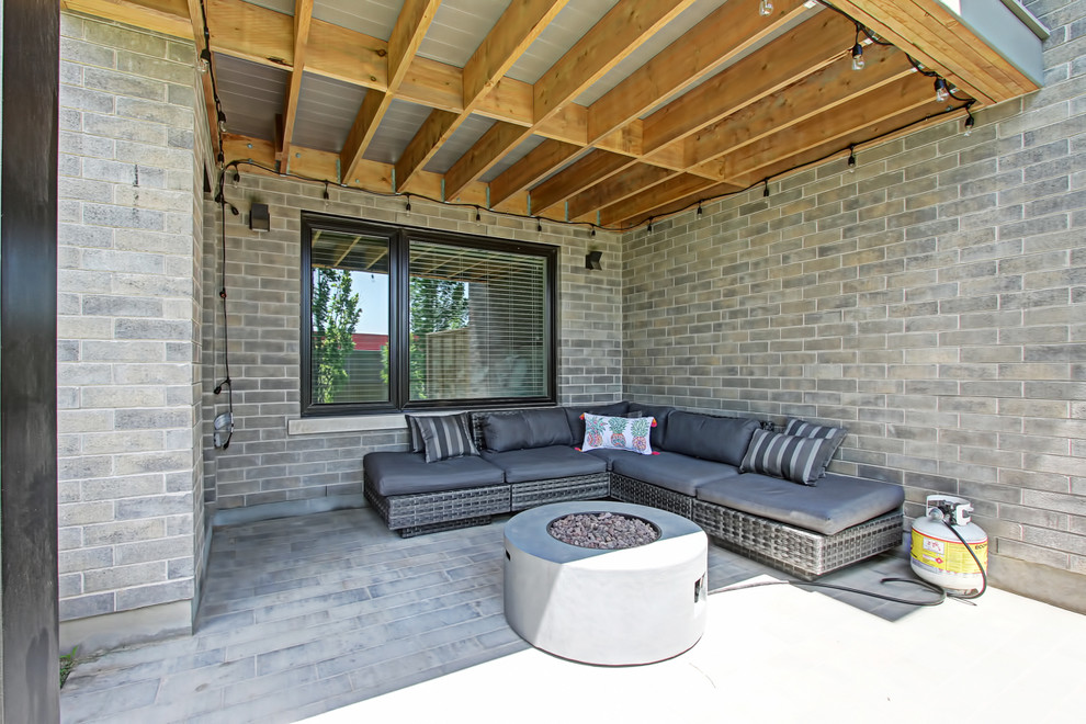 Idées déco pour une terrasse arrière classique de taille moyenne avec un foyer extérieur, des pavés en brique et une extension de toiture.