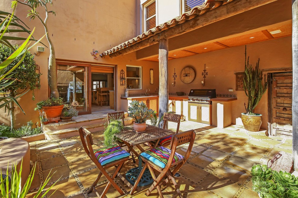 Cette image montre une terrasse sud-ouest américain avec une cuisine d'été, des pavés en béton et une extension de toiture.