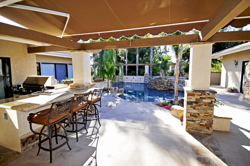 Idées déco pour une terrasse arrière méditerranéenne de taille moyenne avec une cuisine d'été, une dalle de béton et un auvent.