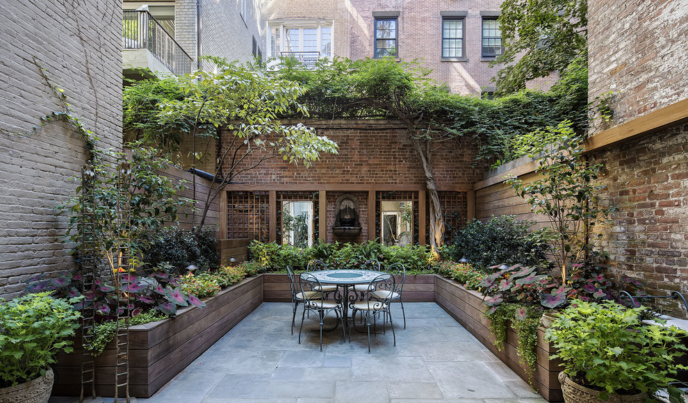 Immagine di un grande patio o portico tradizionale dietro casa con un giardino in vaso, nessuna copertura e pavimentazioni in pietra naturale