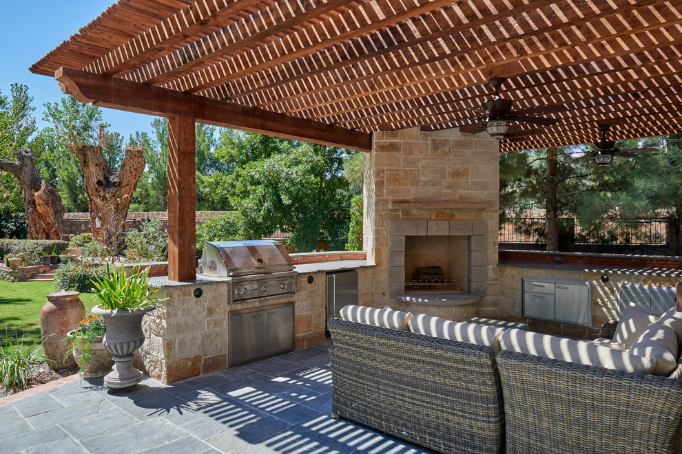 Idée de décoration pour une terrasse arrière tradition avec une cuisine d'été, des pavés en pierre naturelle et une pergola.