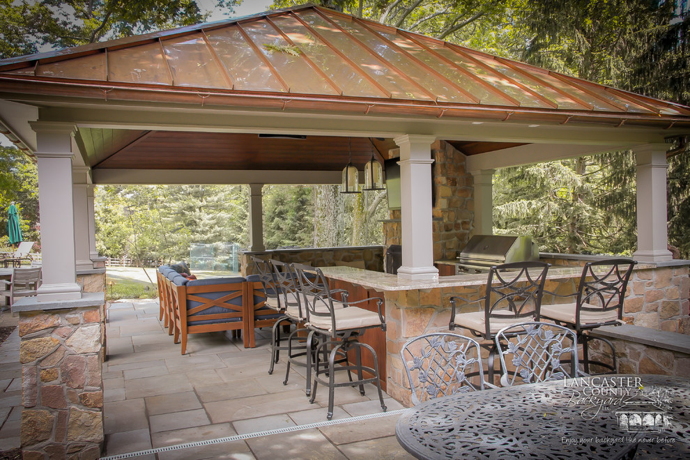 Example of a large classic backyard concrete paver patio kitchen design in Other with a gazebo